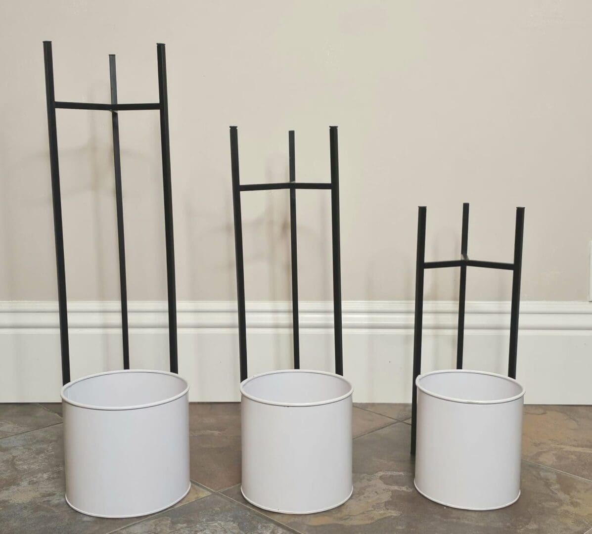 Three white buckets with black metal poles in them.