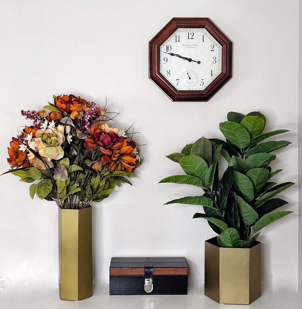 A clock and two vases with flowers in them