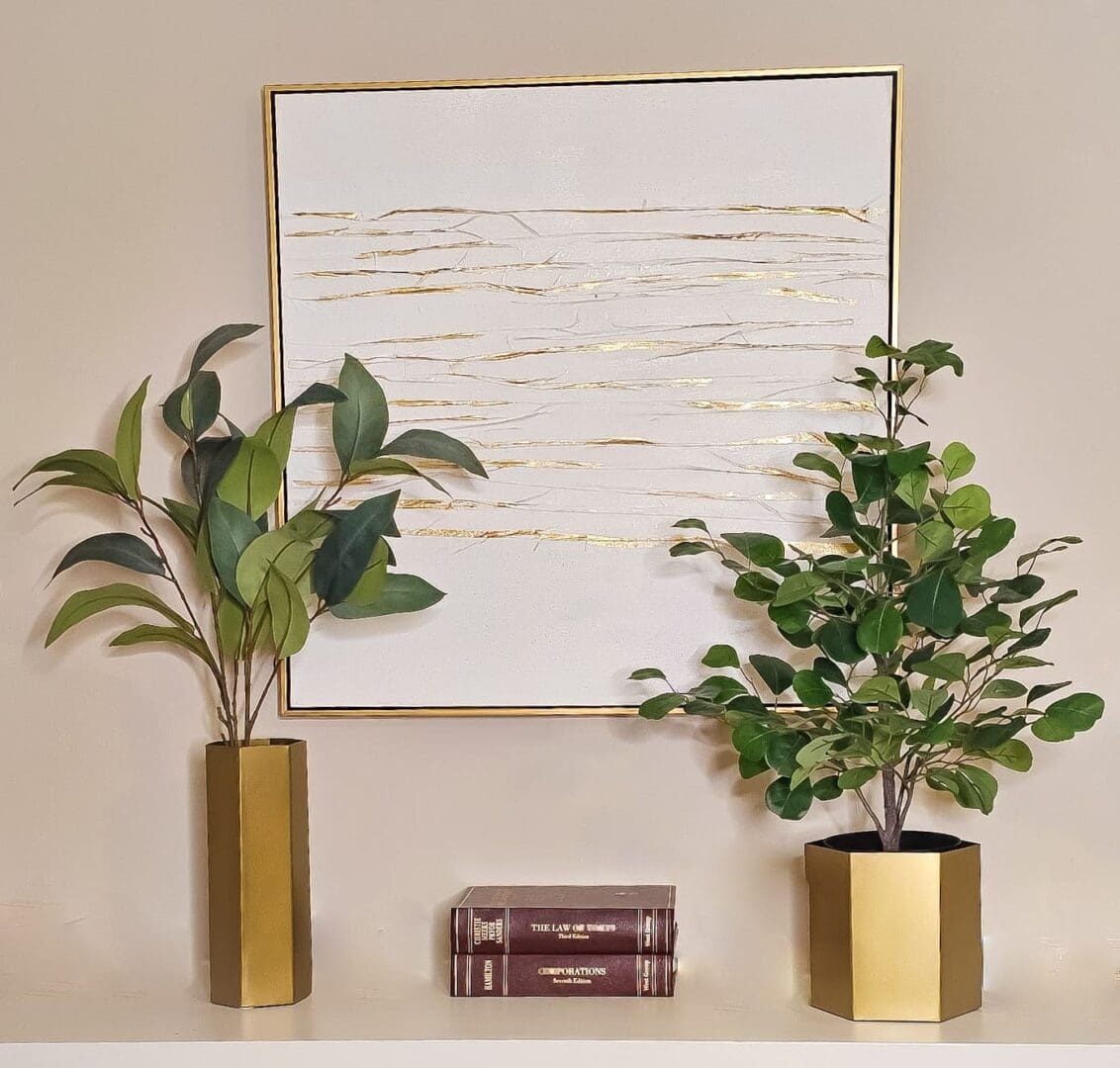 A couple of plants in front of a painting.