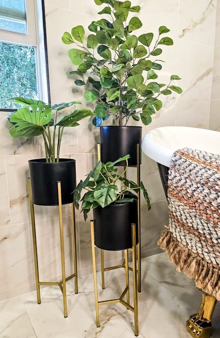 Three black planters sitting on top of gold stands.