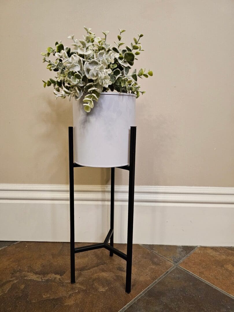 A plant stand with a white pot and some green plants